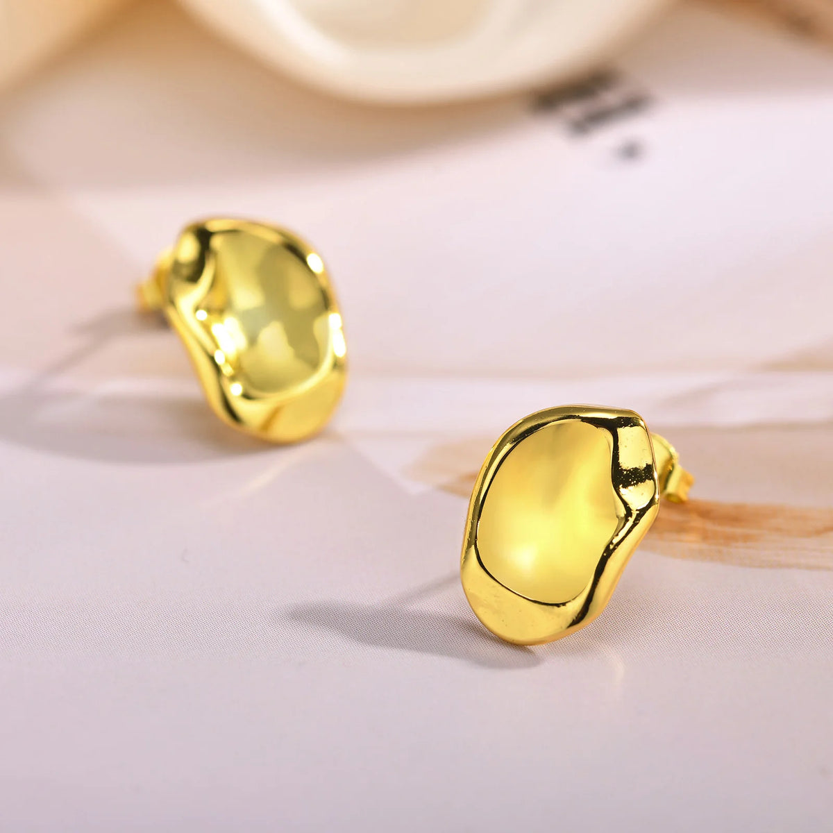Geometric gold-tone stud earrings with shiny oval fronts and post backs