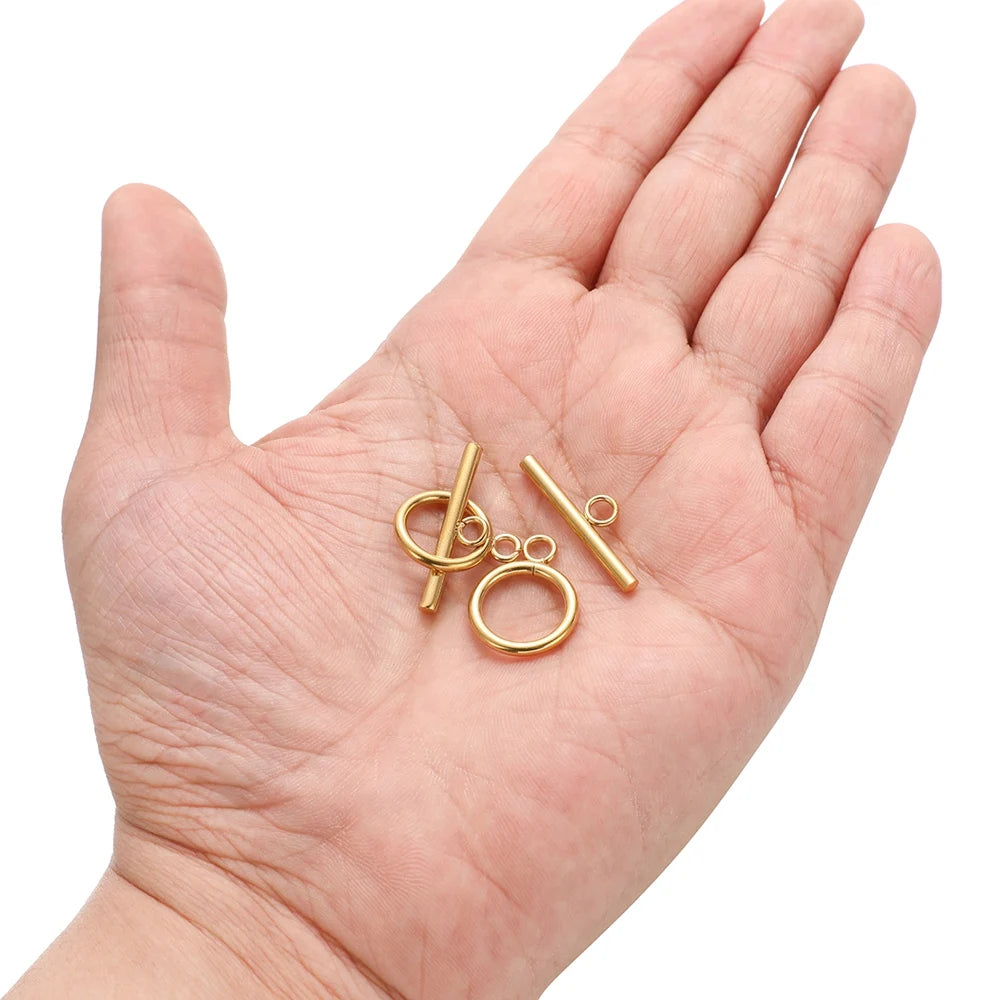 Gold-tone OT clasp toggle parts in hand: ring loops and straight bar connectors