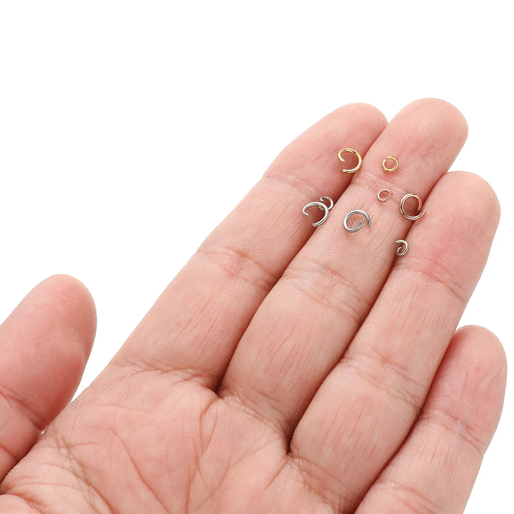 Hand holding small rose gold split jump rings, round open connectors