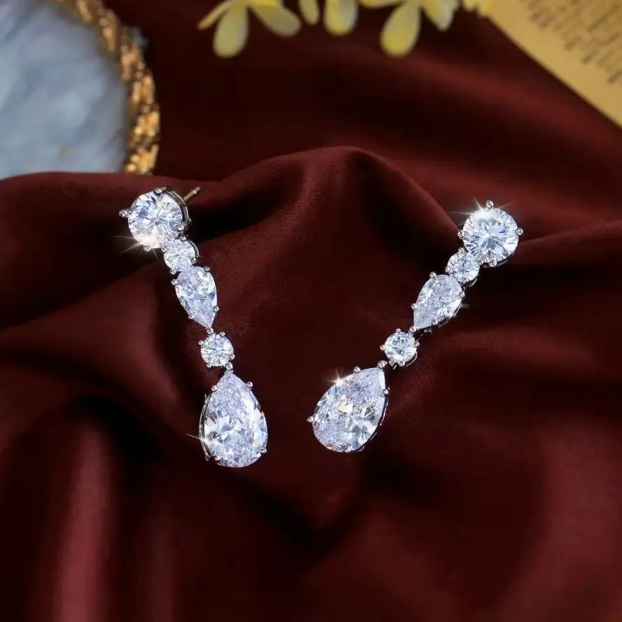 Pair of sparkling cubic zirconia earrings with linked stones and pear-shaped drops.