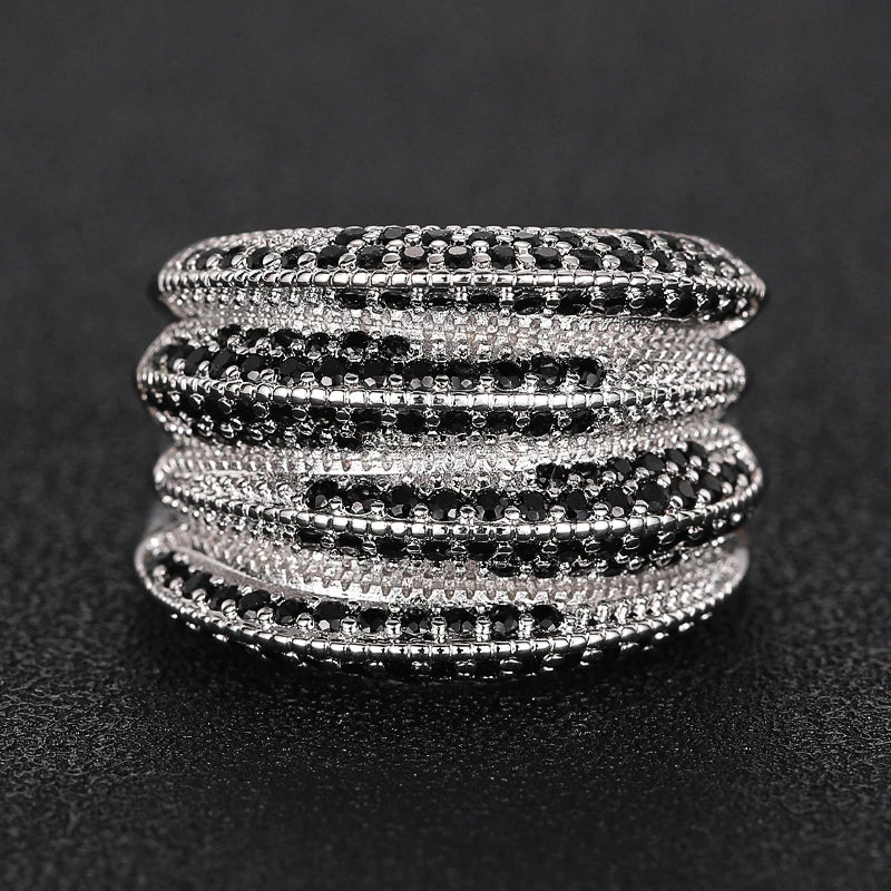 Silver-tone ring shown from the side, with layered bands set with black and clear stones