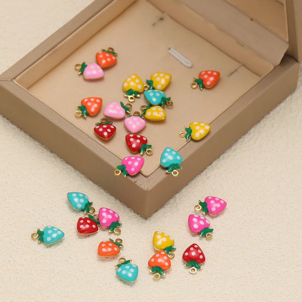 Strawberry charms in assorted colors inside a jewelry box, each with a gold-tone loop
