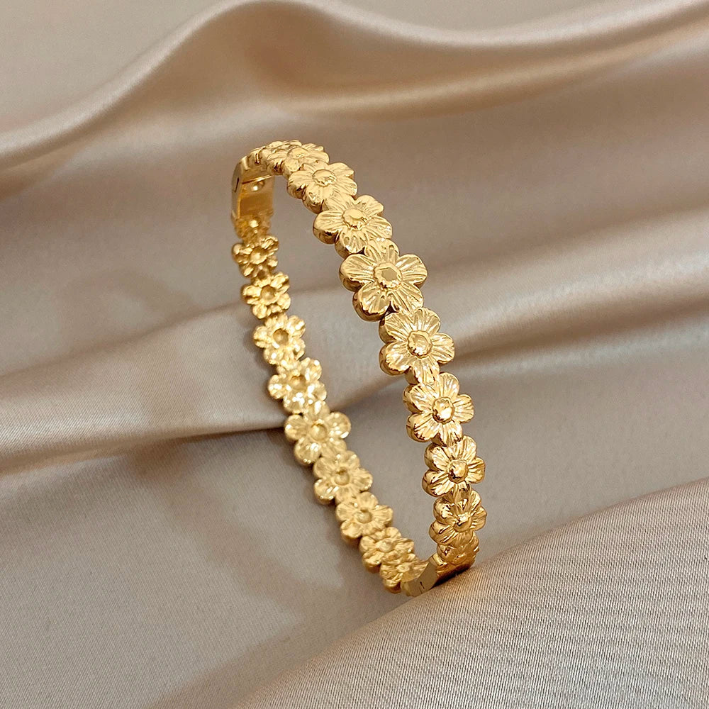 Two gold tone floral heart motif bangles with raised flower detailing