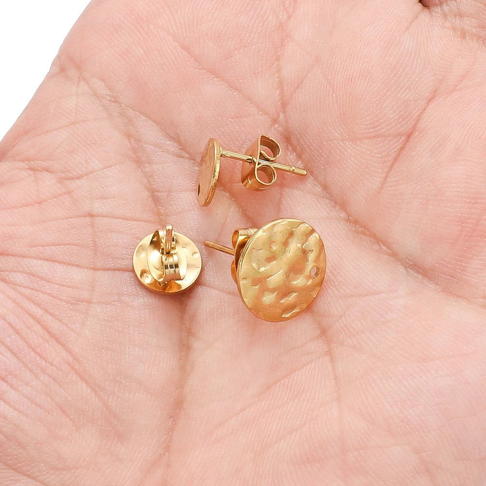 Gold-tone round embossed stud earrings on palm, ripple disc fronts with post backs