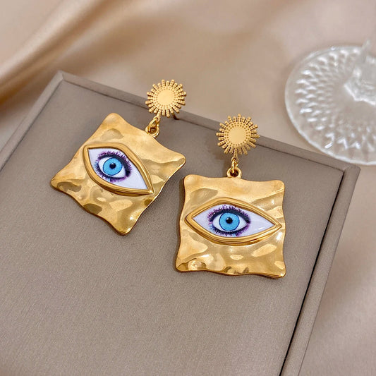 Gold-tone hammered square drop earrings with blue evil-eye eye motif and sunburst tops