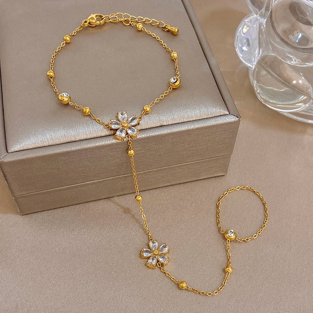 Gold-plated flower charm bracelet with central flower and finger ring chain