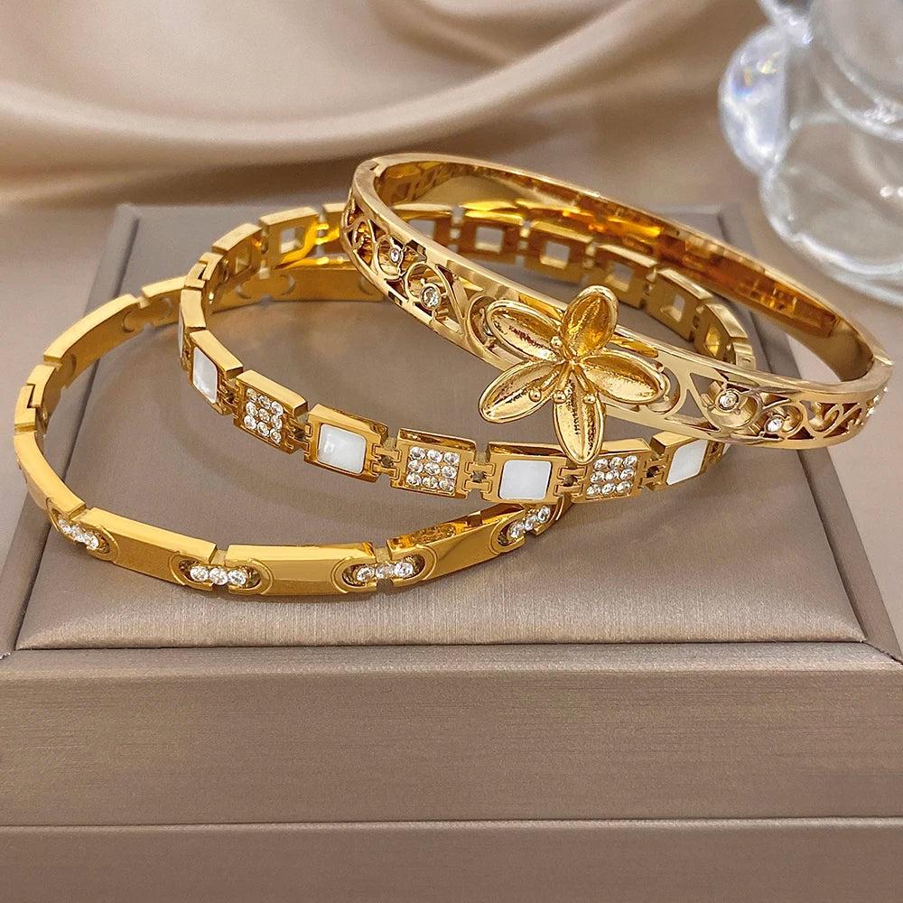 Gold-plated flower and geometric cuff bangles with square crystal insets, stacked