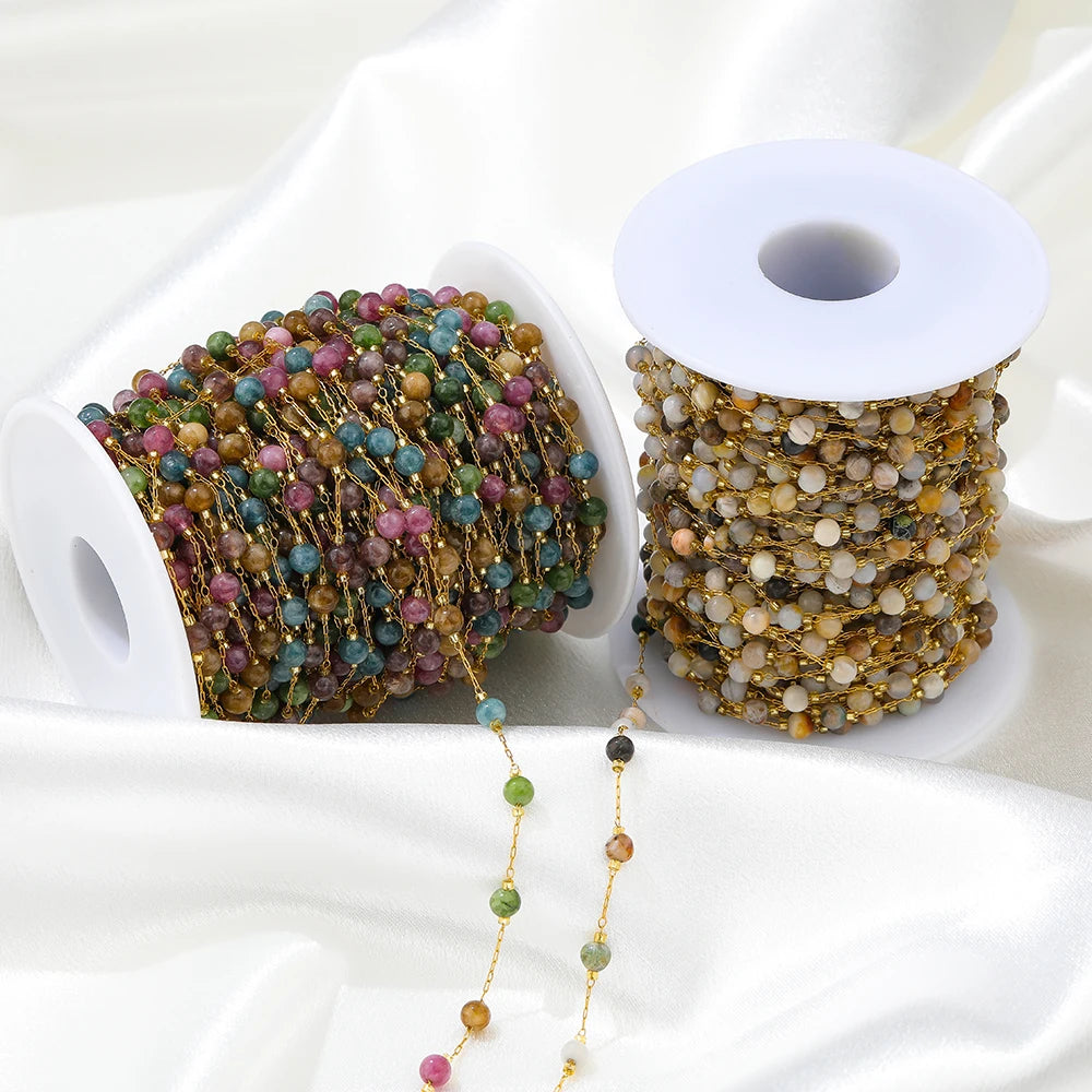 Gemstone bead chain on gold wire spools with multicolor beads, purple and teal tones