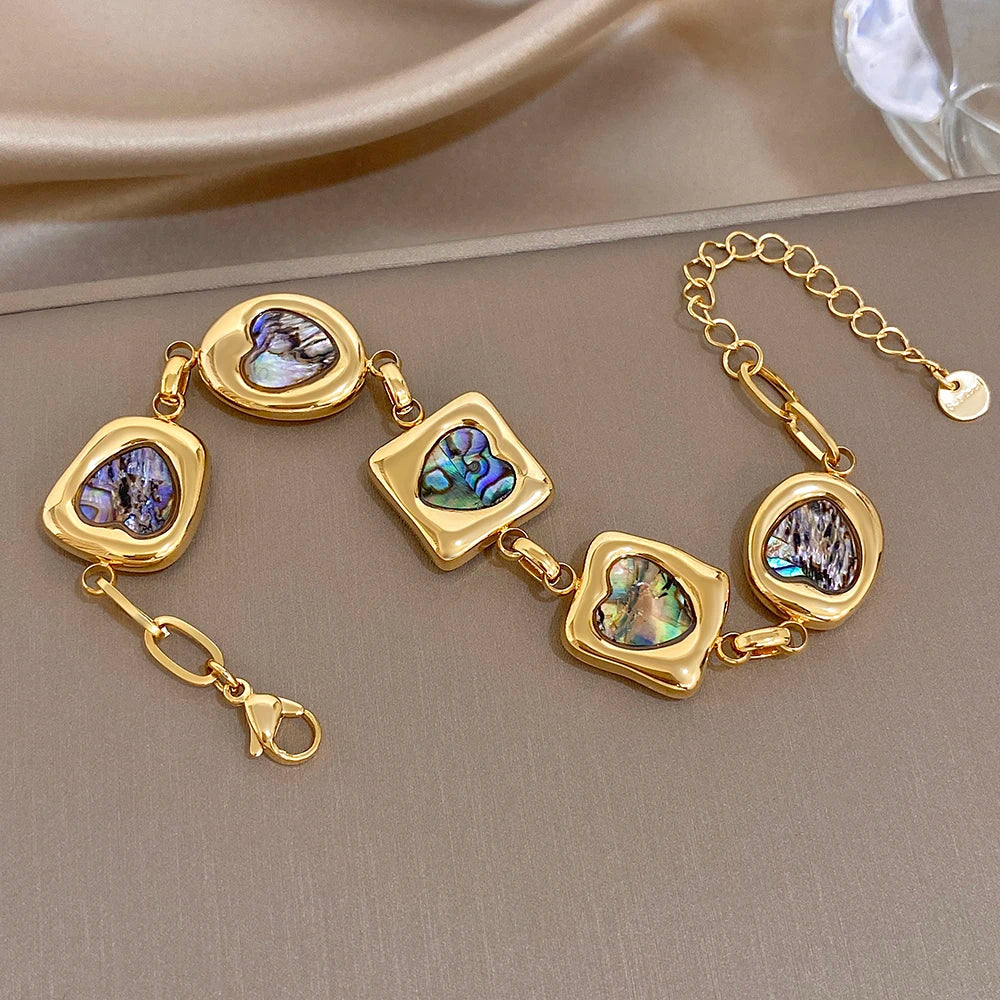 Gold-tone chain bracelet featuring iridescent abalone-shell heart and square charms