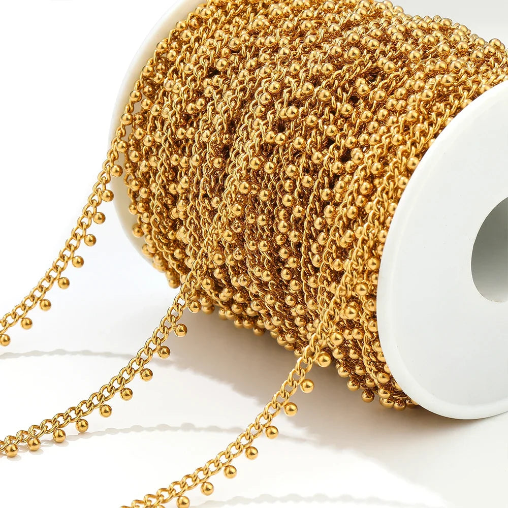 Gold beaded curb link chain on spool, with ball drop chain strands