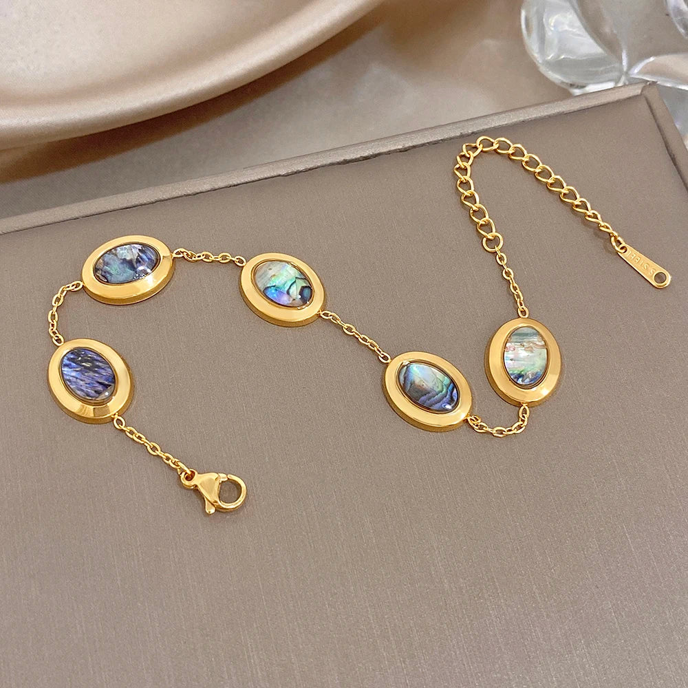 Gold plated adjustable bracelet with blue and iridescent abalone shell oval charms
