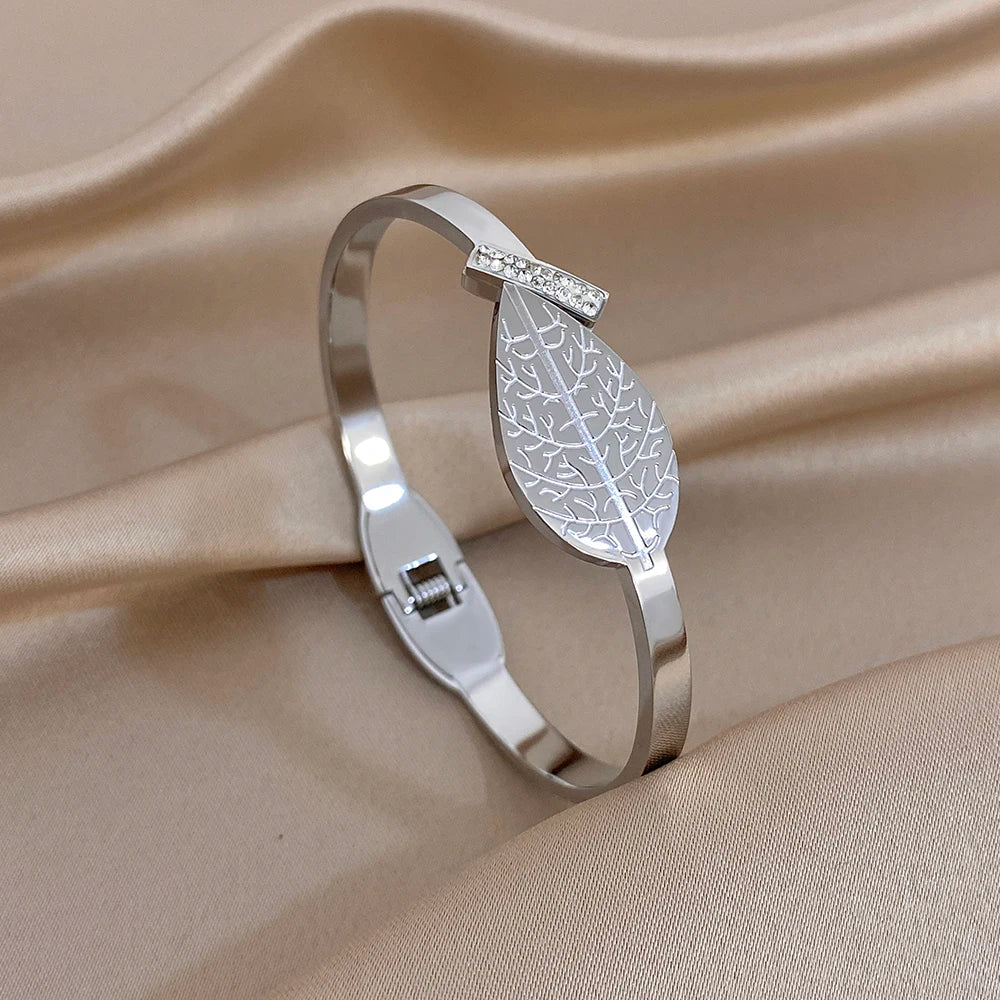 Silver leaf-pattern cuff bangle with rhinestone square detail and hinged clasp.