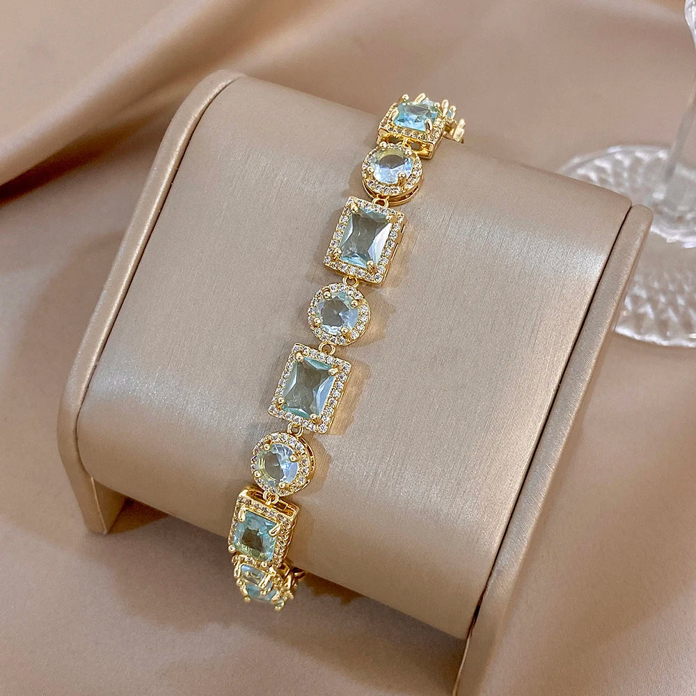 Gold-tone bracelet with blue square and oval stones and round links, flexible chain style