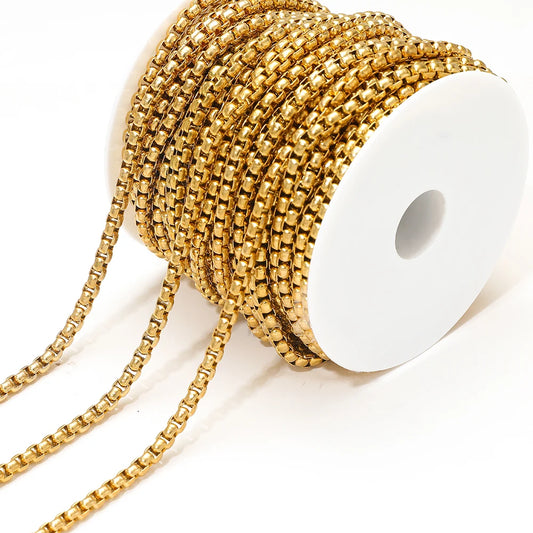 Gold rolo box chain, coiled with rectangular link pattern on white card