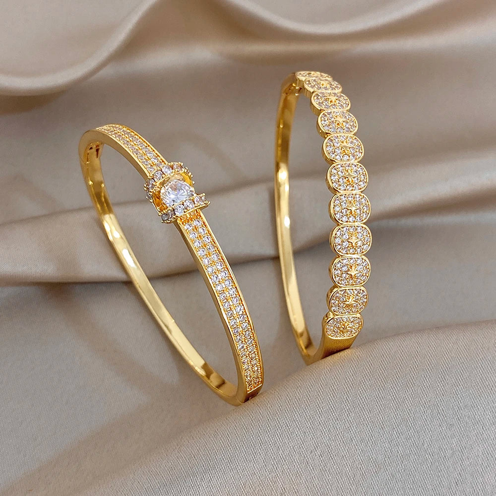 Gold plated rhinestone bangle bracelets, one with star center and one with pavé oval links