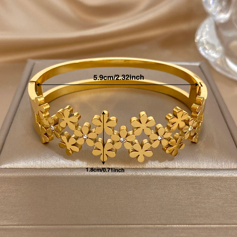 Gold-plated wide bangle with flower motif row and sparkling crystal accents