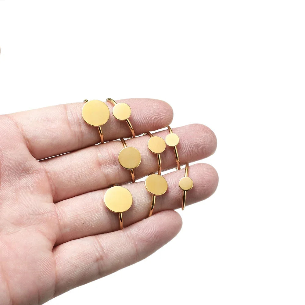 Gold-plated ring blanks with round cabochon bezel discs held in hand