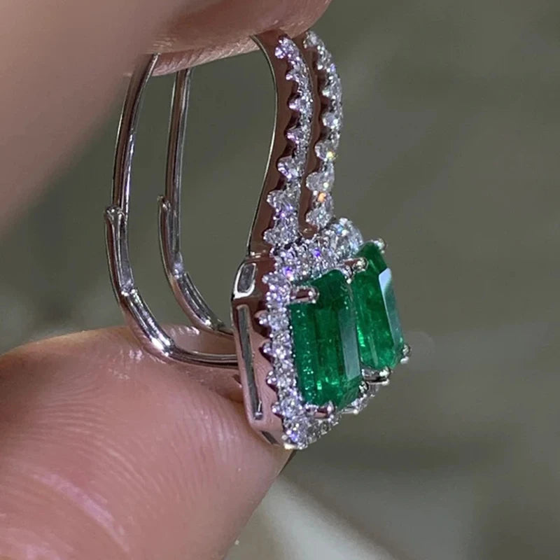 Side view of silver-tone earrings showing green stones, clear accents, and hinged hooks
