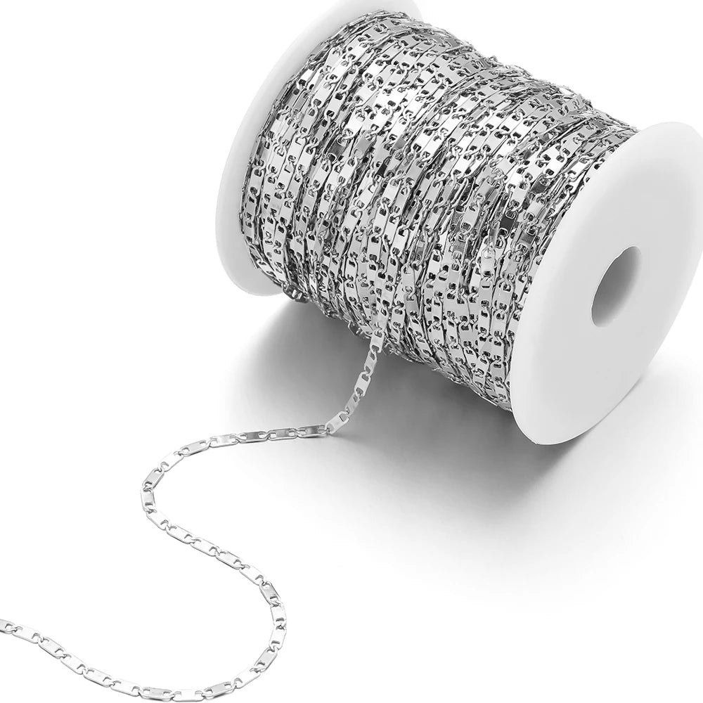 Silver stainless steel flat link chain on a white spool for bracelet making