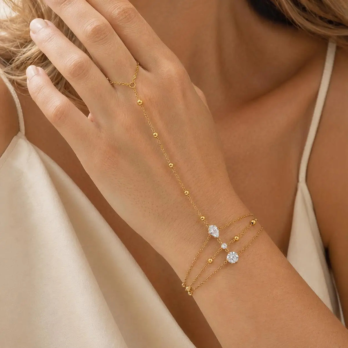 Gold-tone layered heart CZ hand chain bracelet on wrist and fingers