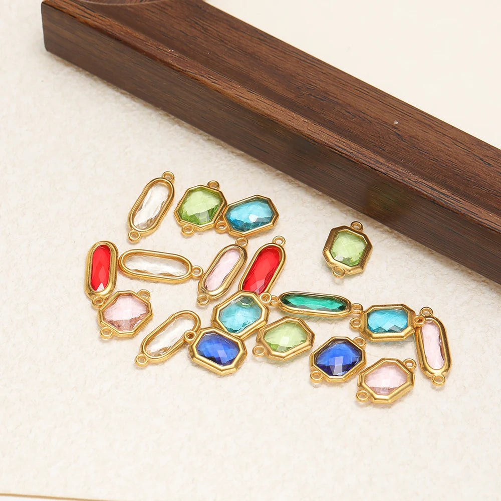 Assorted faceted glass charm connectors with gold-tone frames and loops, mixed colors