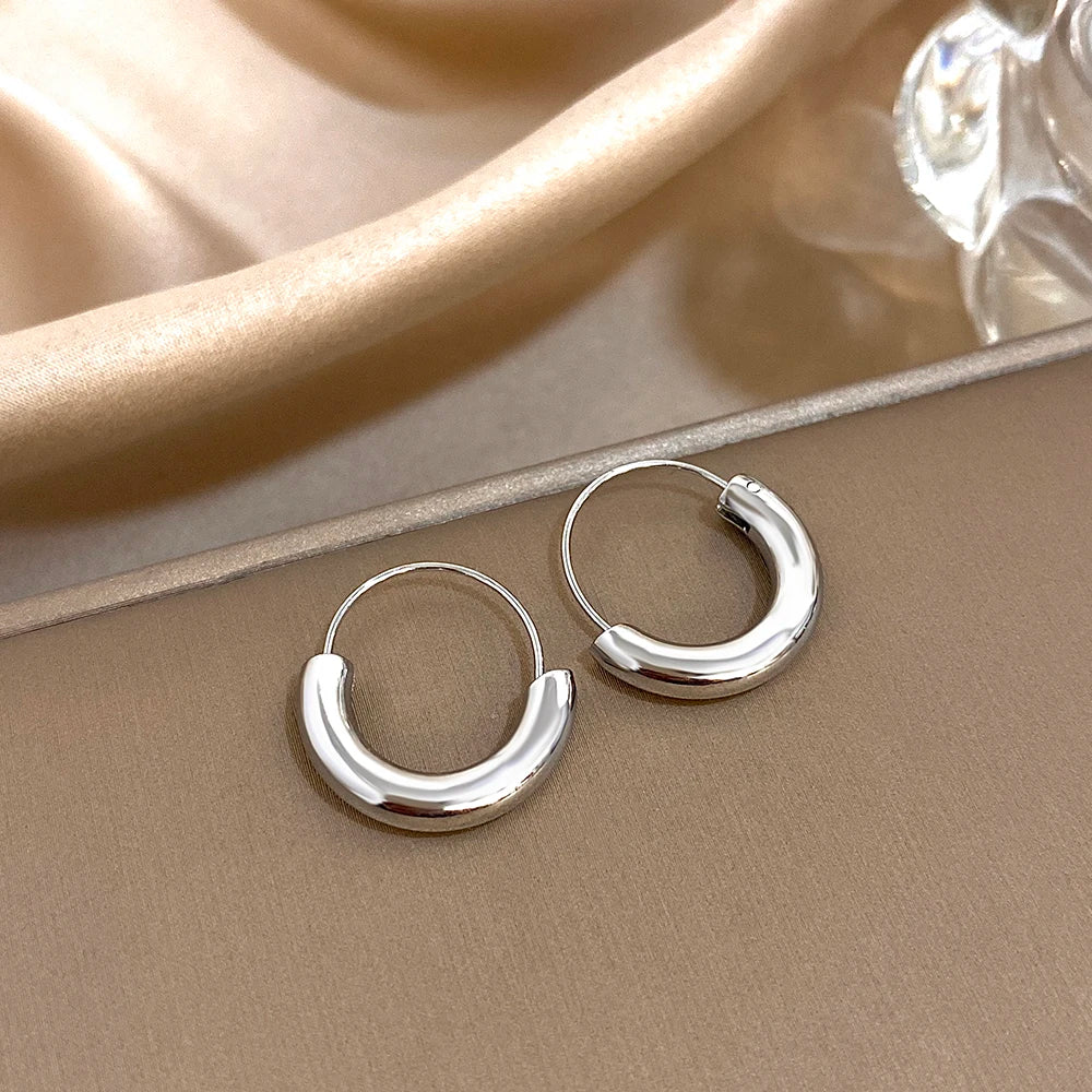 Silver-tone geometric hoop earrings with glossy, rounded lower halves