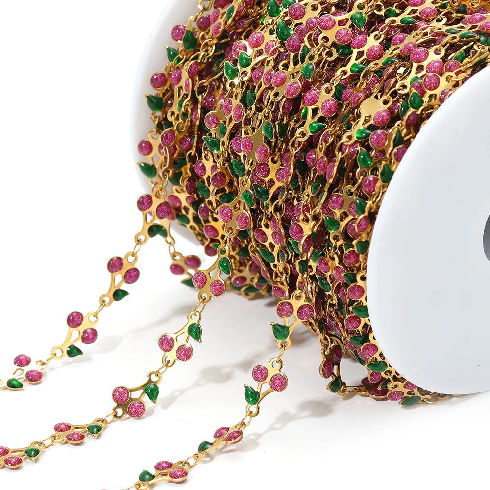 Close-up cherry charm chain with gold links and pink enamel flowers, multicolor accents