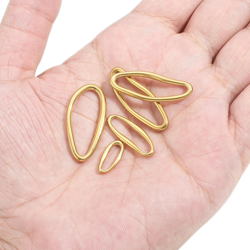 Gold irregular oval metal charm links in a hand, small jewelry findings