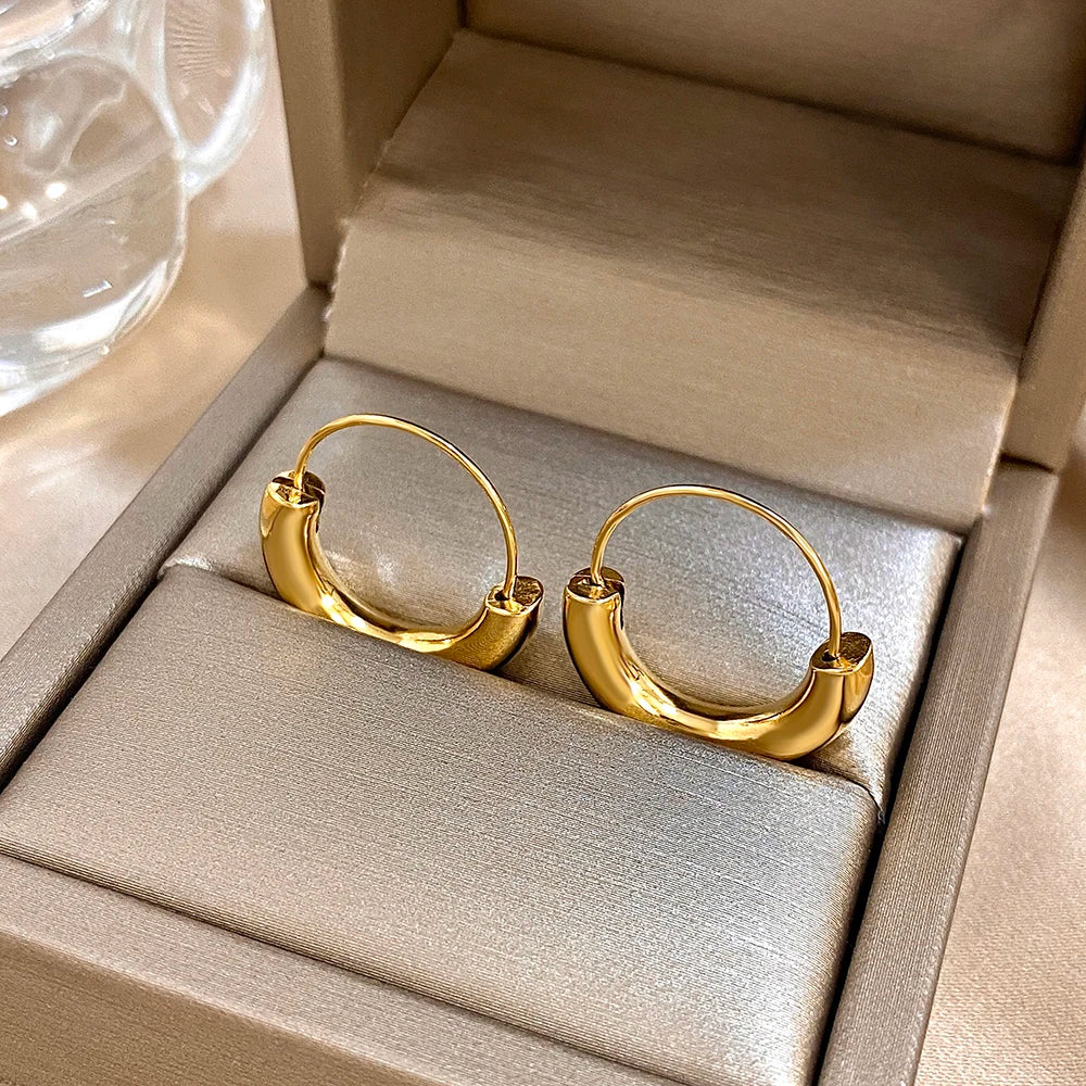 Gold-tone geometric hoop earrings viewed from the back, showing their hinged closures