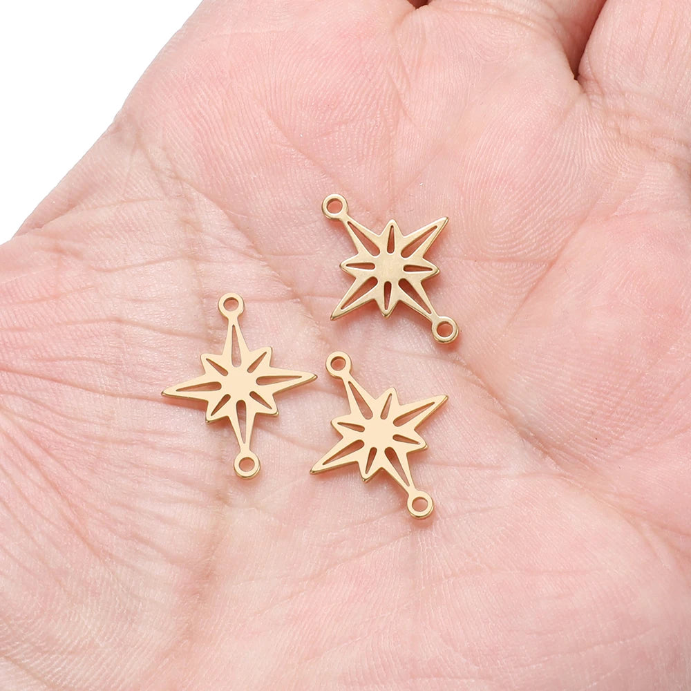 Gold-tone snowflake star charms with attachment loops on a hand palm
