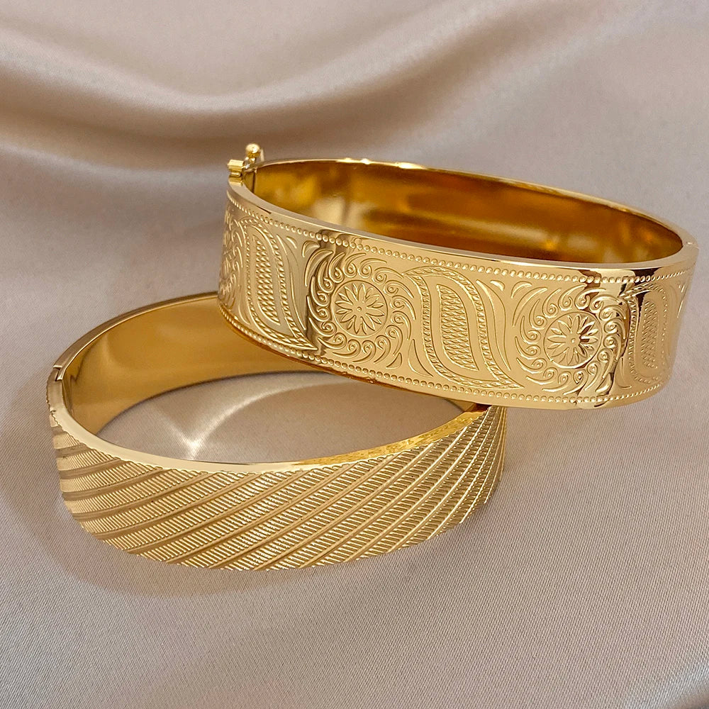 Gold-tone wide cuff bangle pair with etched geometric texture and floral accents