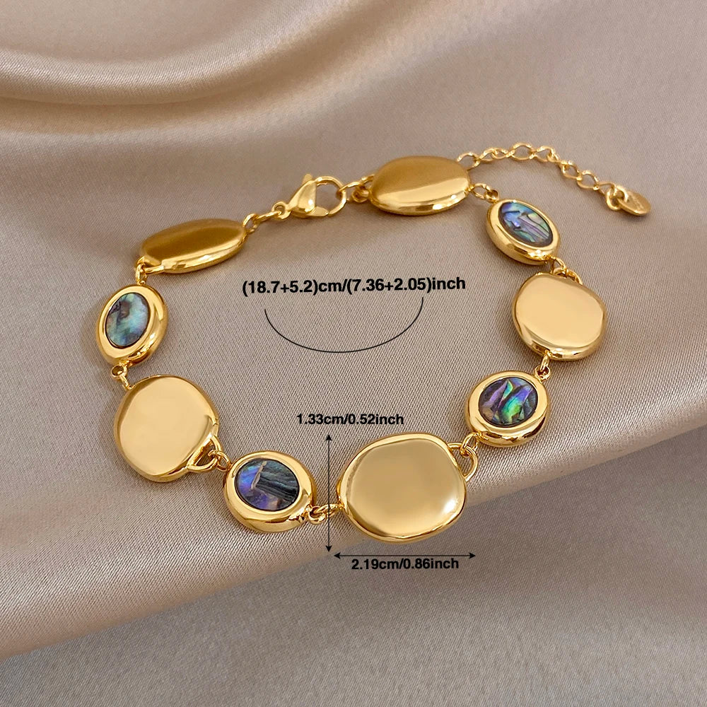 Gold-tone chain bracelet with oval discs, iridescent abalone shell beads, and clasp