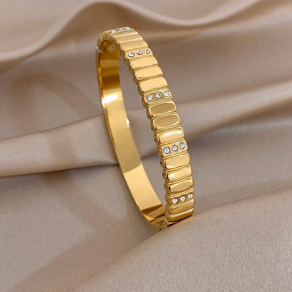 Gold-tone slim cuff bangle with rhinestone row and textured band segments