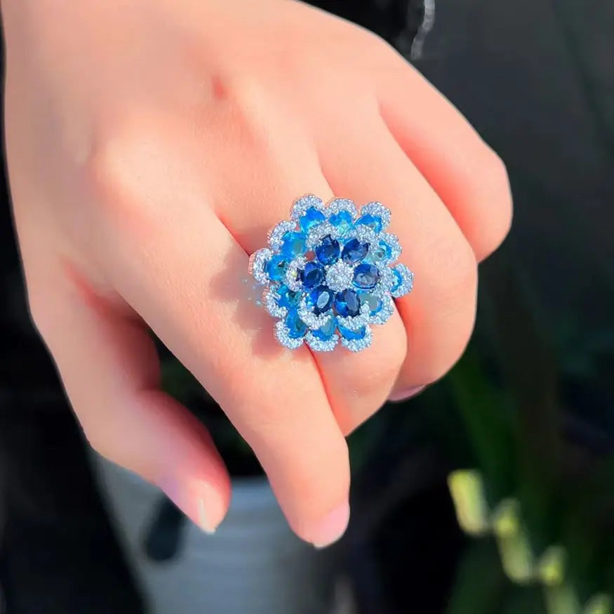 Blue flower statement ring with layered sparkling stones, worn on a finger