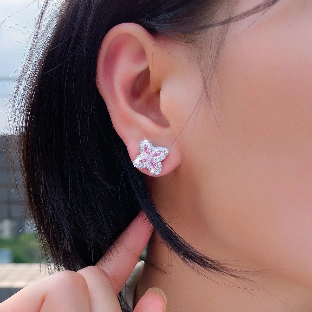 Four-leaf cubic zirconia stud earring with pink stones, worn on an ear