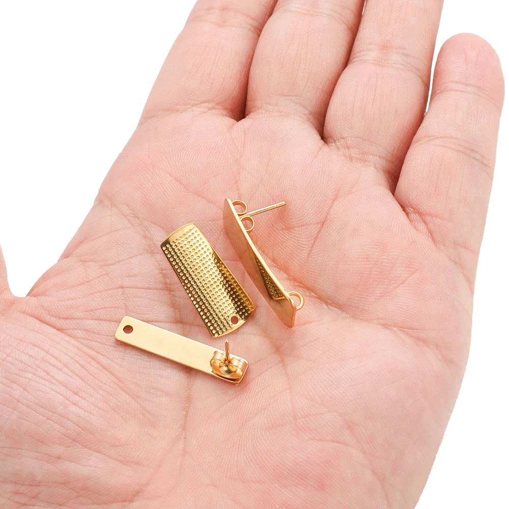 Gold-tone statement earrings on hand, showing textured rectangular and bar styles