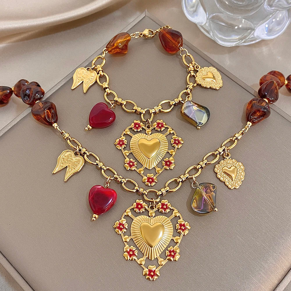 Gold-tone charm bracelet with red hearts, amber beads, heart pendant, and wing charms