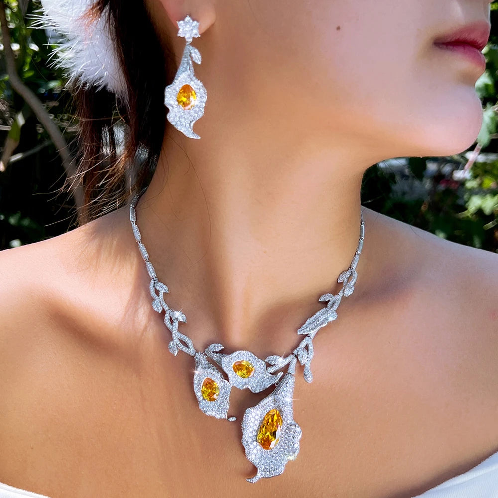 Calla lily jewelry set worn, with a leaf-link necklace and dangling yellow-stone earring