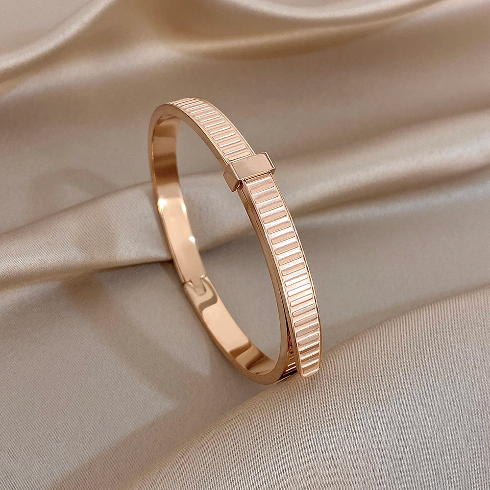 Rose gold geometric ribbed cuff bangle with hinged clasp and smooth frame