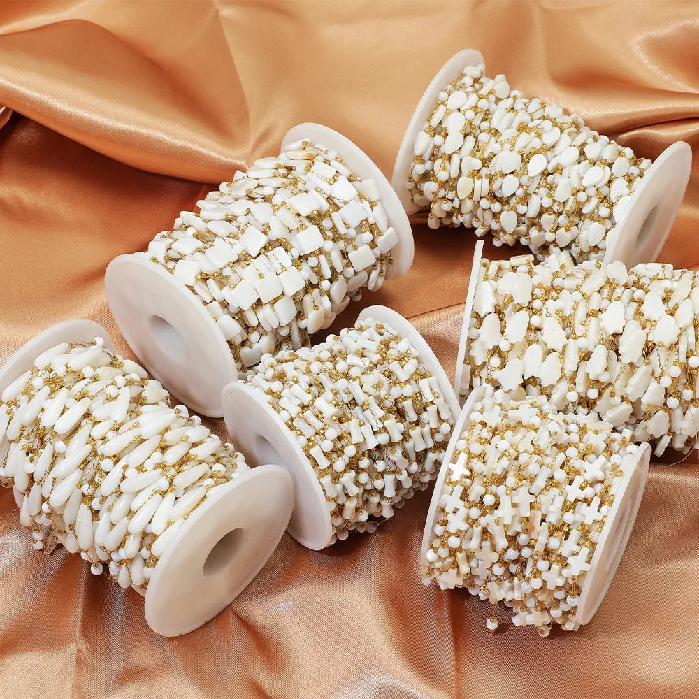 White and gold beaded chain spools arranged on fabric for DIY jewelry supplies