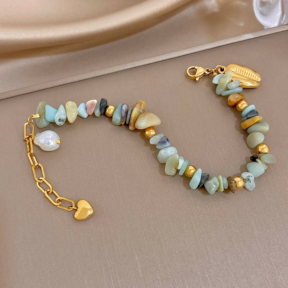 Gold link beaded bracelet with light blue, cream, and brown irregular stones; pearl shell charm