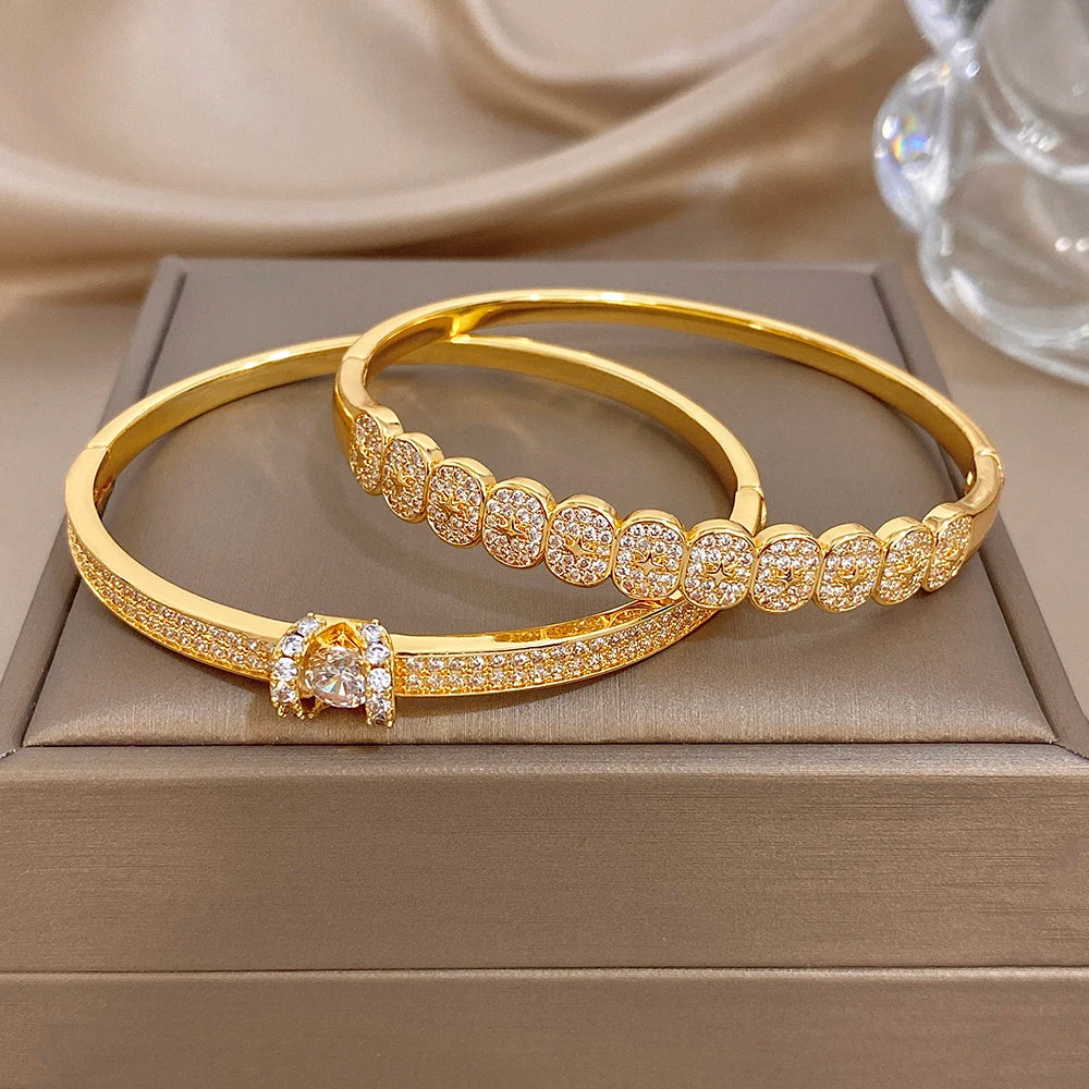 Two gold-tone rhinestone cuff bracelets, one with a star centerpiece