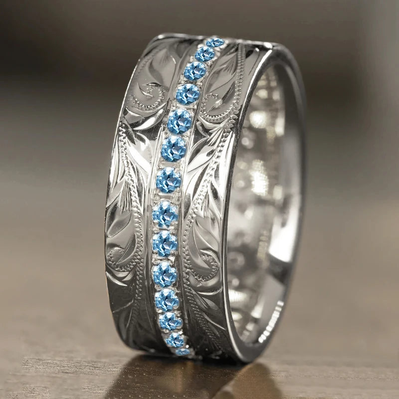 Silver carved wedding band with blue channel-set stones and leaf engraved outer band