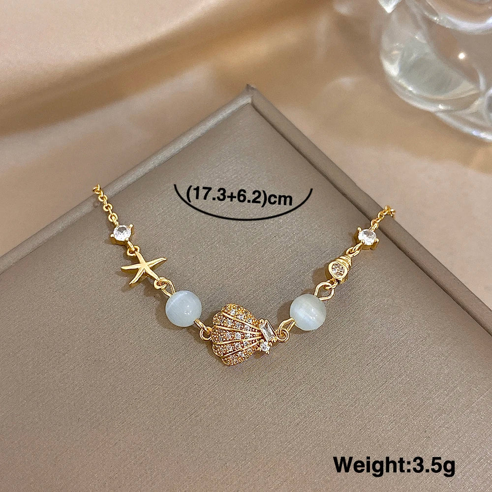 Gold-tone bracelet with starfish and shell charms, moonstone-style beads, rhinestone centerpiece