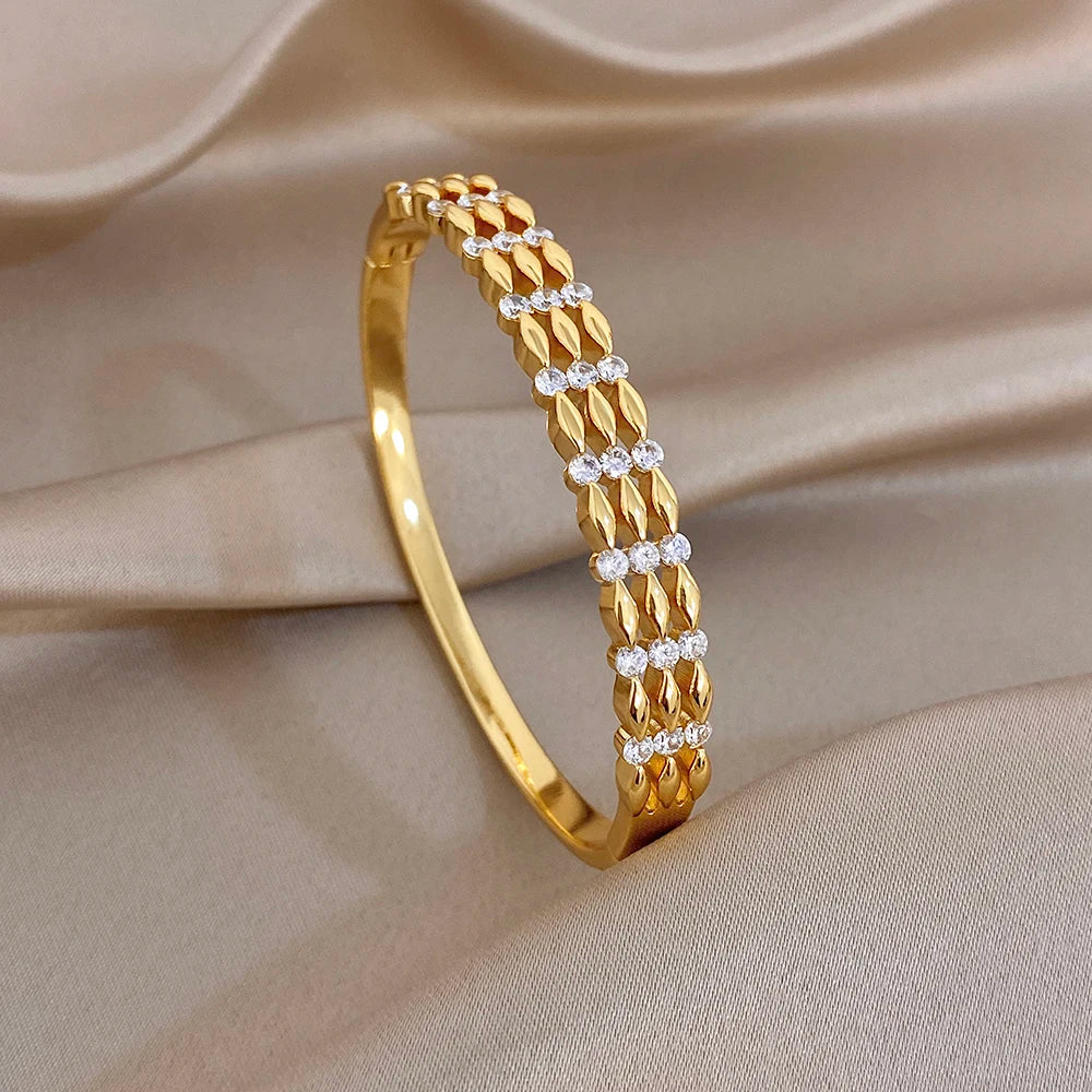 Gold-tone cuff bangle with vertical textured link row and round crystal stone accents
