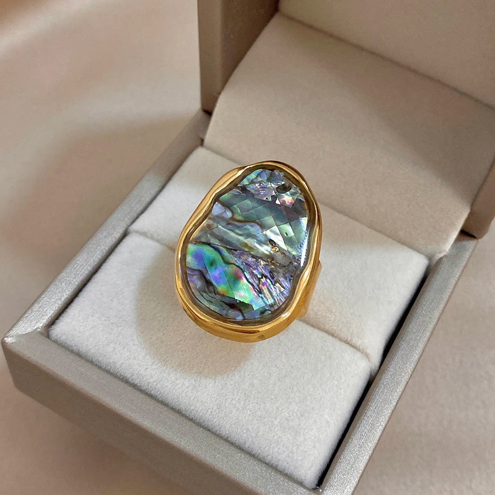 Gold-plated abalone shell ring displayed in a white jewelry box, iridescent oval stone