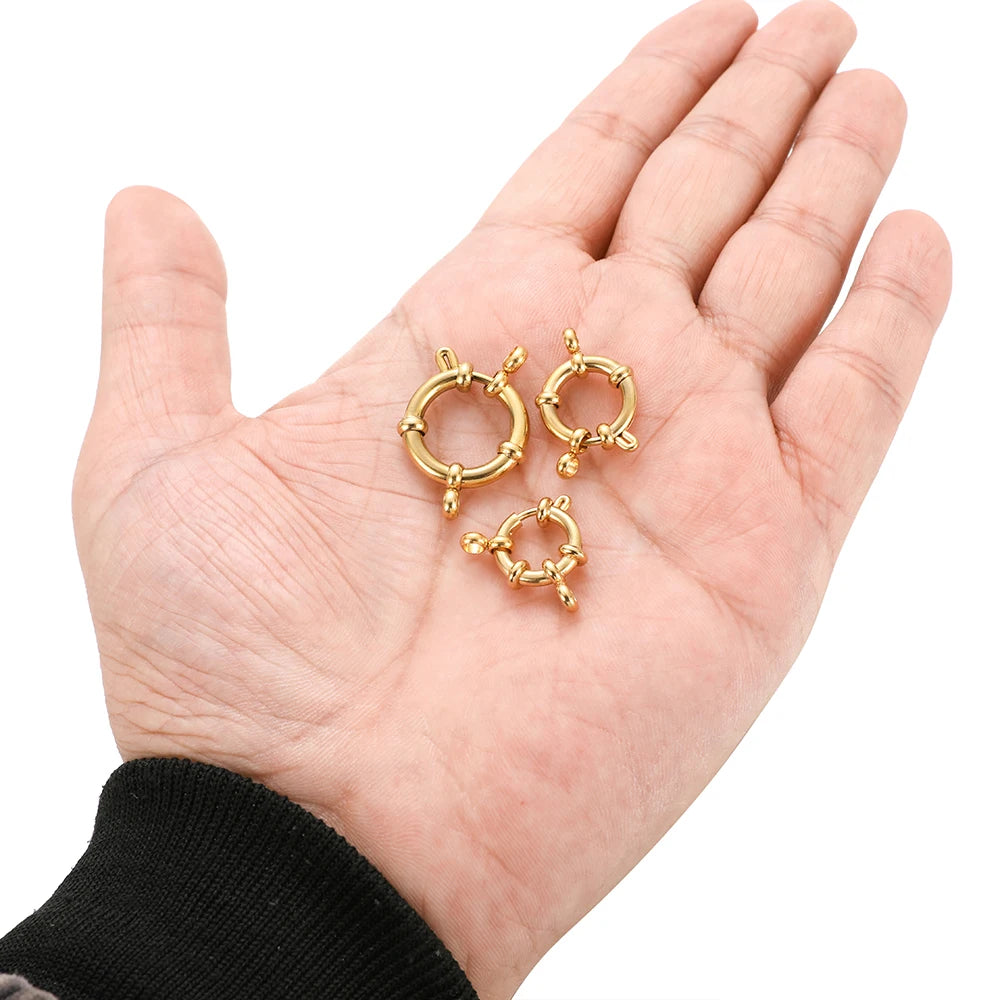 Gold spring clasp hooks held in hand, round hinged latch connector findings