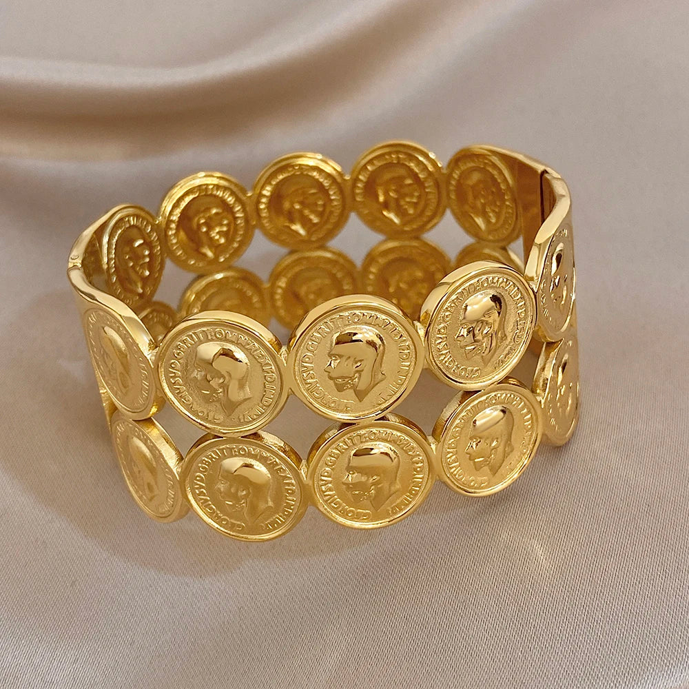 Gold plated wide cuff bracelet with round coin discs and human face emblems