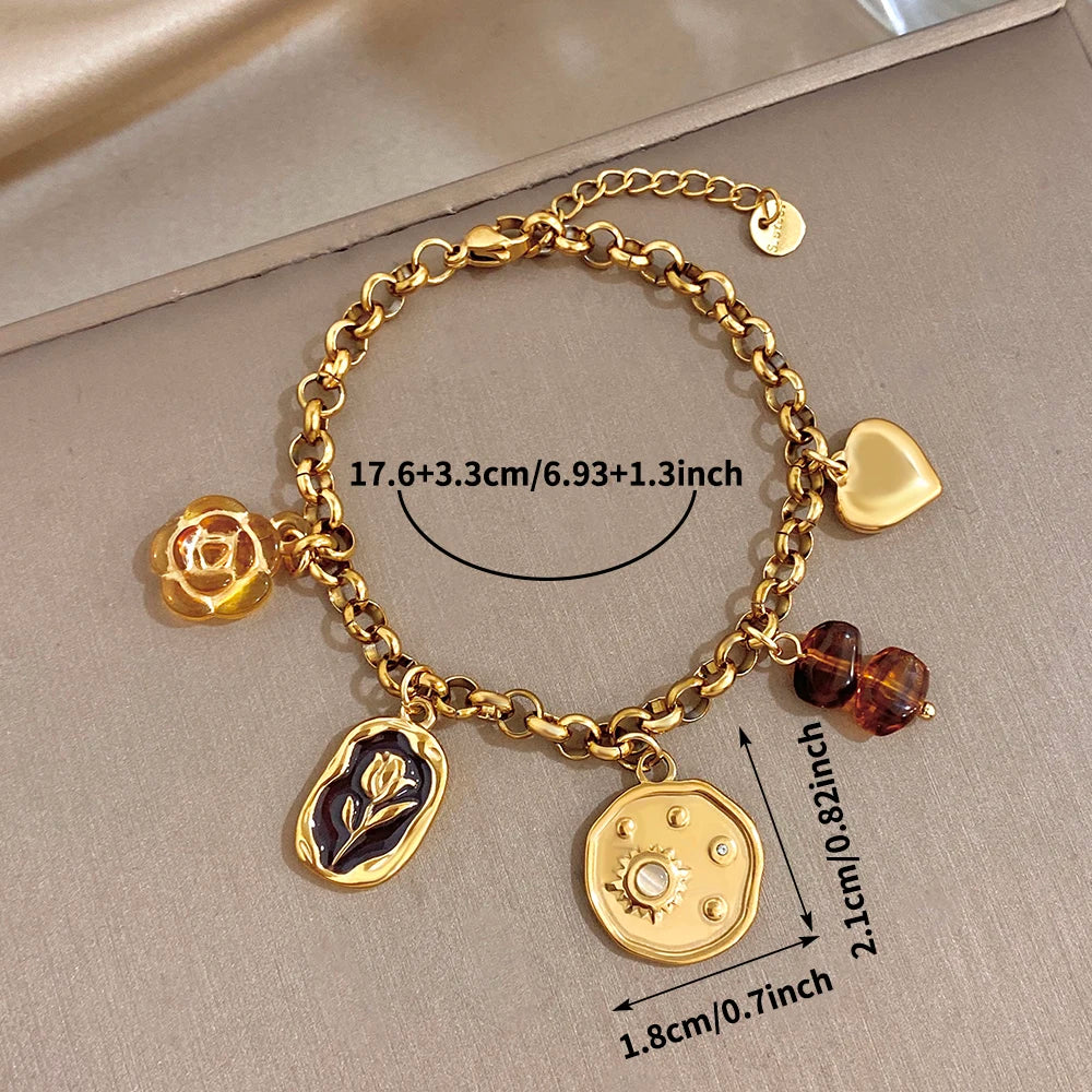 Gold charm wristband with rose, leaf, coin, heart, and amber bead dangles