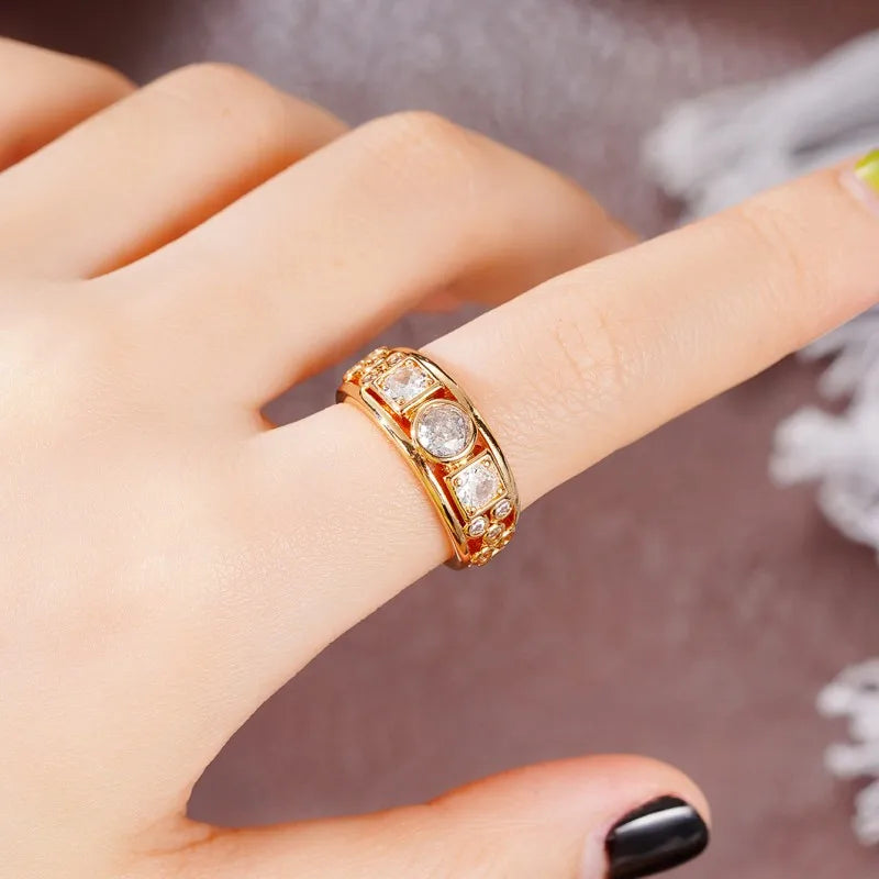 Gold-tone CZ ring on finger with square center stone and round side stones